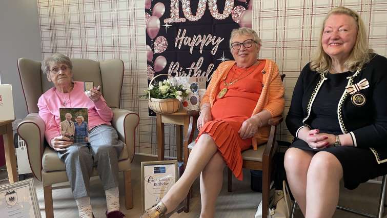 Margaret Harrower holding her Women's Land Army medal, sitting next to Provost Margaret Cooper and Deputy Lieutenant for Lanarkshire Margaret Morton