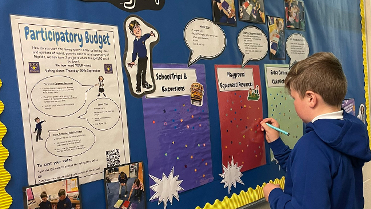 pupil writing something on a school noticeboard