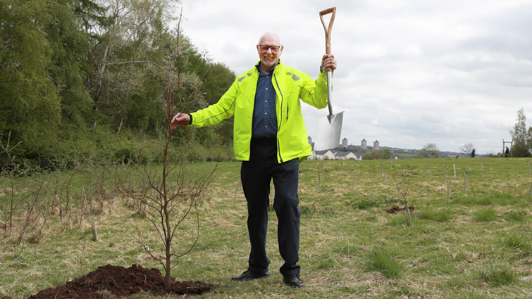 This image shows Council Leader John Ross planting a tree at Chatelherault