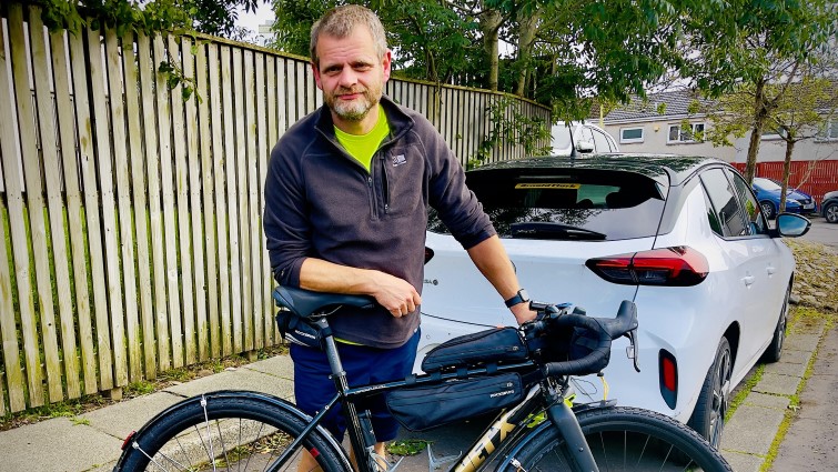 This image shows BetterPoints app user Jason with his bike and a car in the background