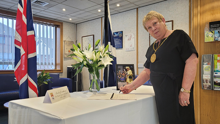 This image shows the Provost Margaret Cooper signing the book of condolence following the death of HM The Queen