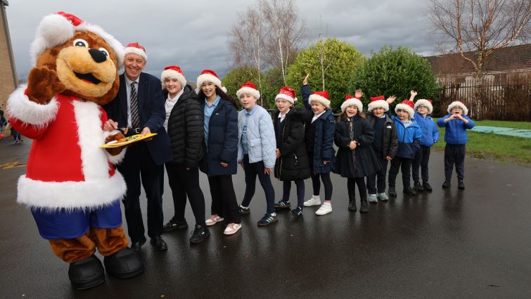 This image shows pupils in a line with the school mascot Bankie and Councillor Robert Brown following a special Christmas lunch