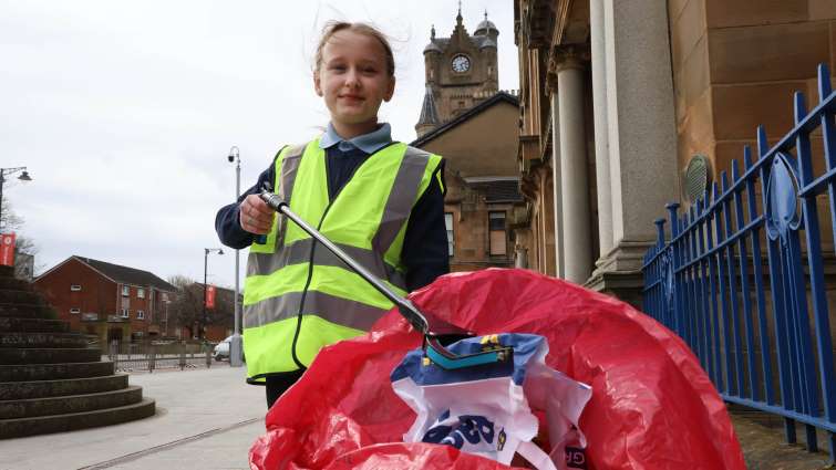 Pupil picking litter using council picking stick and red refuse bag