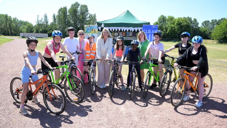 this photo shows a groups of youngsters standing in a semi circle each with a bike and wearing a helmet. Three of the council officers involved in the event are pictured with them in front of one of the gazebos at Strathclyde Park.