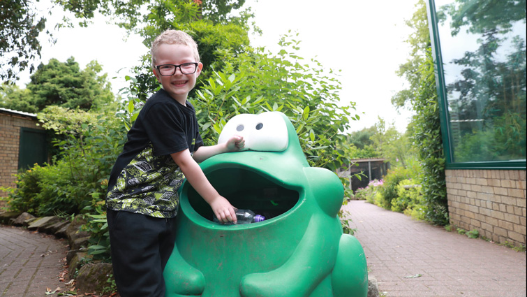 This photo shows a seven year old boy visiting Calderglen Zoo and depositing rubbish in the novelty frog bins on site.