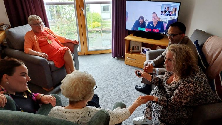 This photo shows Catherine Bryan and her daughter Kate alongside Professor Sengupta and Provost Cooper with a Smart TV and video call in the background