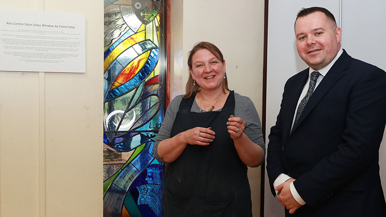 This photo shows artist Fiona Foley, standing next to council leader, councillor Joe Fagan as they both admire the stained glass window.