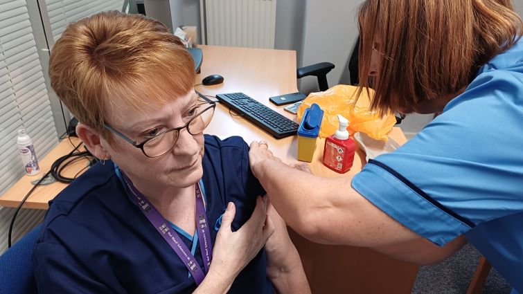 This image shows a council worker receiving her flu vaccination