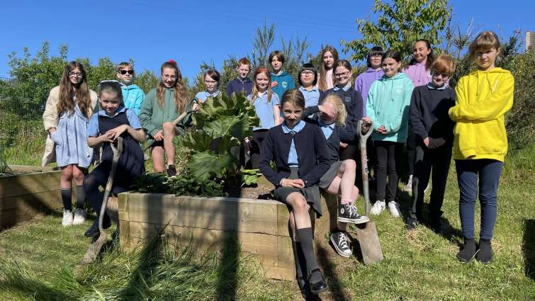group of primary school pupils next to fruit and veg raised beds