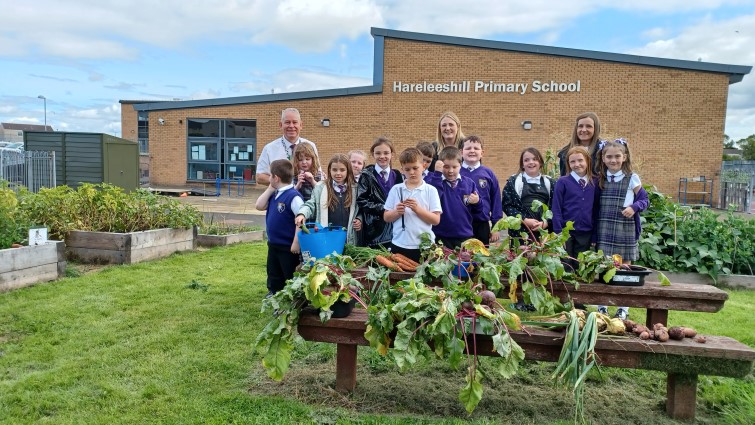 children outside Harelesshill Primary School with some of the vegetables they grew