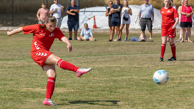 This image shows a member of the girls' football team striking the ball at the ICG 2022 in Coventry