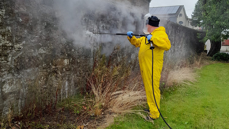 A South Lanarkshire Council worker cleans graffiti from a wall.