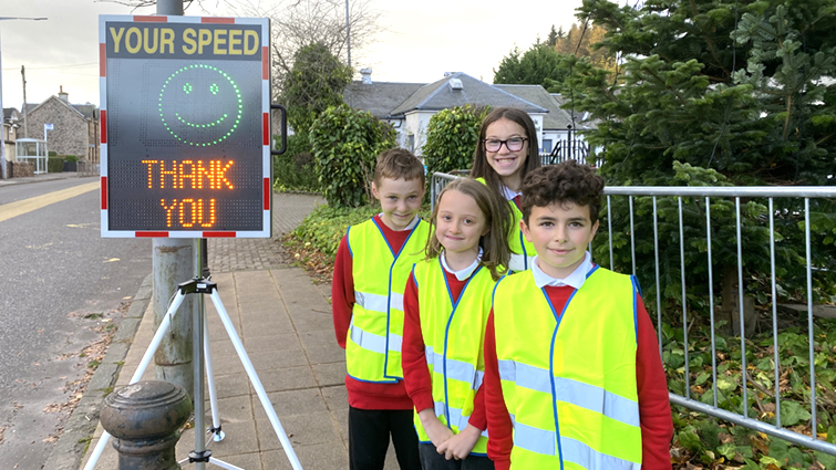 this image shows the Junior Road Safety Officers from Kirkfieldbank Primary School monitoring the speed of vehicles passing their school