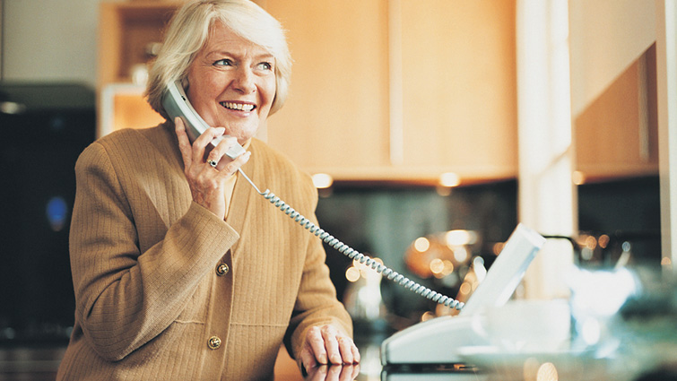This image shows a woman on a traditional landline telephone