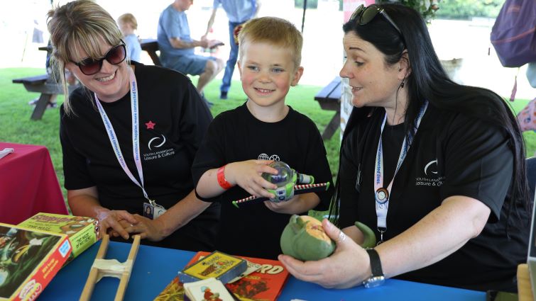 This image shows museums staff with a young person at the Community Race Day at Hamilton Park