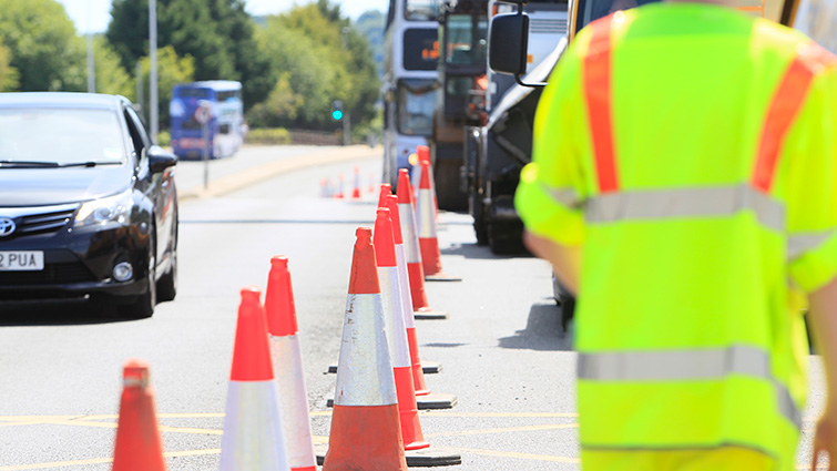 A car drives past a line of traffic cones as a South Lanarkshire Council team carry out road resurfacing