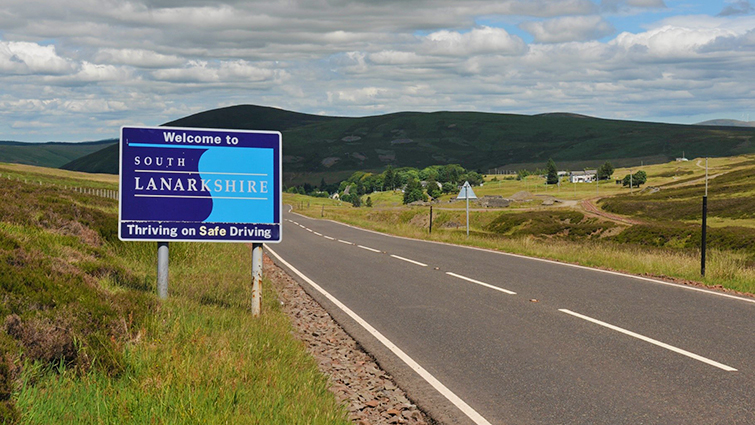 This image shows a view of a rural road in Clydesdale with a Welcome to South Lanarkshire sign in the foreground