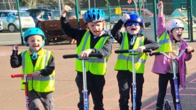 primary pupils on scooters wearing safety gear