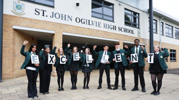 This images shows pupils from St John Ogilvie High School outside the school holding up letters which spell out the work excellent following a very impressive HMI report