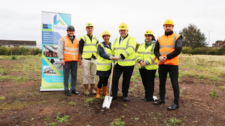 This image show Councillor Davie McLachlan with council officials and contractors as a shovel is placed in the ground to signify work beginning at a new council housing site in Watson Street, Larkhall