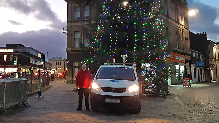 This image shows one of our community wardens in front of the Christmas tree in Hamilton