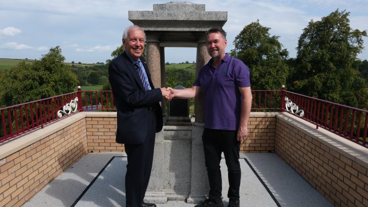 This image shows Councillor Robert Brown and John Young from Friends of Stonehouse Park shaking hands at the fountain at Alexander Hamilton Memorial Park in Stonehouse following work to restore it