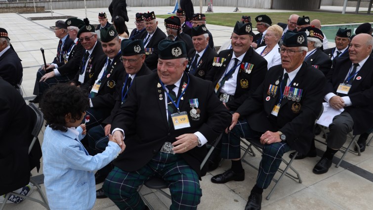 This image shows a young child shaking the hands of veterans at the Freedom of South Lanarkshire event