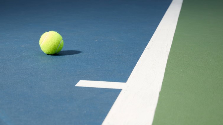 This is a generic image of a tennis ball resting on a court 