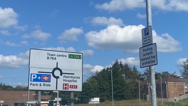 This image shows a sign at Hairmyres Rail Station with directions to the current park and ride facility