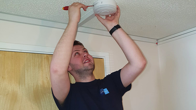 This image shows a council worker fitting a smoke alarm
