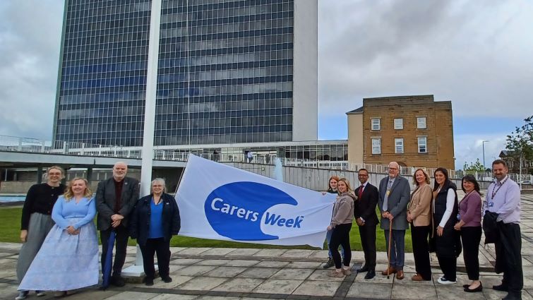 Carers, partner charity representatives and SLC representatives at the raising of the Carers Week flag in June 2026.